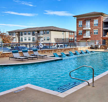 A swimming pool surrounded by lounge chairs and buildings in the background.at Century Cedar Hill, Texas